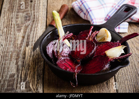 Roasted beetroots in cast iron skillet on wooden rustic table Stock Photo