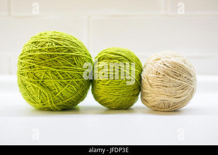 A green woolen ball made of thread and knitting needles for hobbies.Yarn for knitting. Handmade Stock Photo