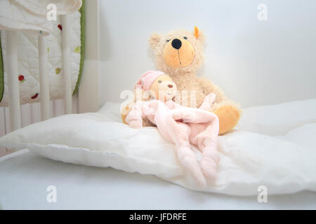 Two teddy bears in baby cott sitting on white pillow. Crib lovingly prepared by mother for the baby to be born Stock Photo