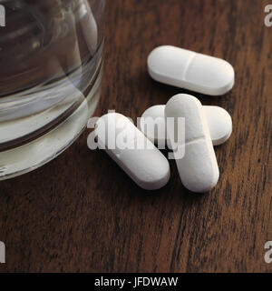Tablets and a glass of water on a table Stock Photo