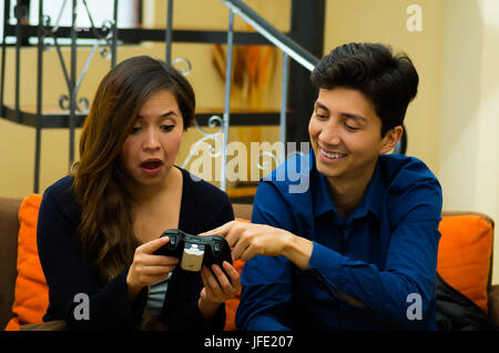 Handsome young man teaching how to play the video games to his girlfriend, on the couch, concept about home entertainment, video games. Stock Photo