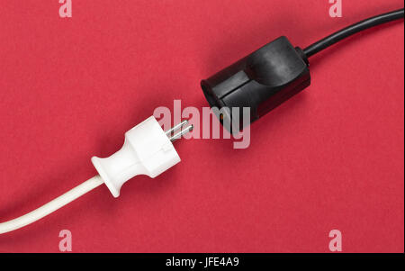 Disconnected white european power cable plug with black connector cable on red background Stock Photo