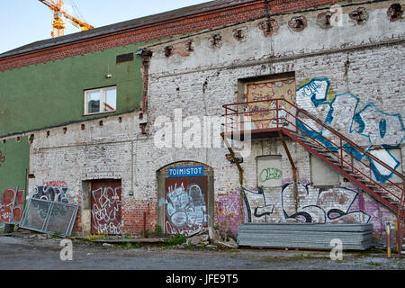 Old railway shed with rusty steel stairway boarded up with graffiti (street art) painted on the walls. Stock Photo