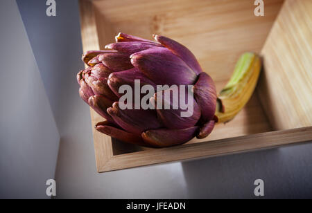 Fresh Artichoke in a square wooden plate. Stock Photo