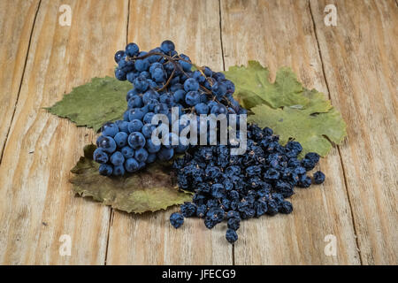 black grapes and raisins on a green vine leaves Stock Photo