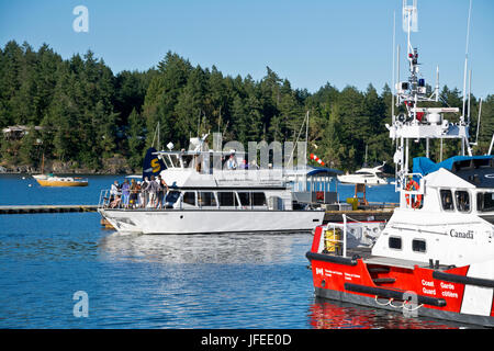 Boat cruise and Canadian coast guard vessel in Ganges harbour on Salt Spring Island, BC, Canada Stock Photo