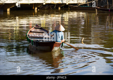 Woman in a rowboat lookoing for tourist customers on the Thu Bon River in Hoi An, Vietnam Stock Photo