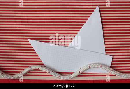 paper yacht on red striped sea Stock Photo