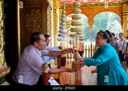 Woman delivering gift to Buddha at the Haw Pha Bang temple, on the Royal Palace grounds in Luang Prabang, Laos, Asia Stock Photo