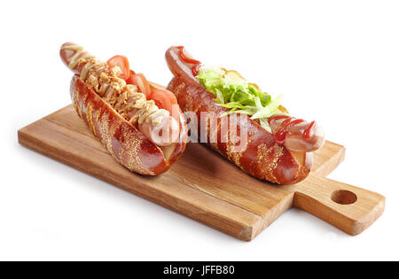 two hot dogs on wooden cutting board isolated on white background Stock Photo