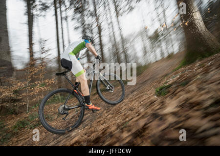 Side view of biker riding in speed through forest Stock Photo