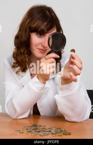 hand hold magnifying glass and coins Stock Photo