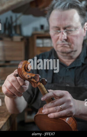 Craftsman in workshop examining violin Stock Photo