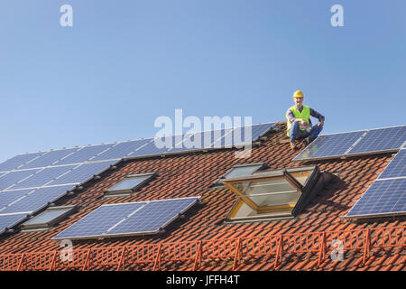 Engineer takes break from installing solar panels on house roof Stock Photo