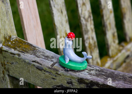 A child's plastic toy of a performing seal and a ball left behind on the arm of a park bench Stock Photo