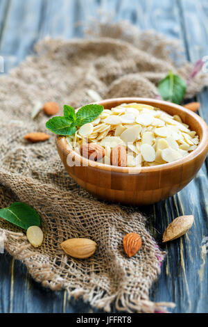 Almond flakes in a wooden bowl on the old sackcloth. Stock Photo