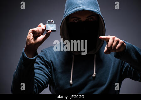 Hacker wearing hood in dark room Stock Photo