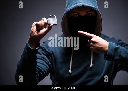 Hacker wearing hood in dark room Stock Photo