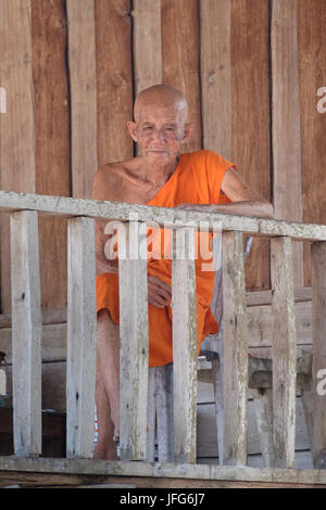 Old buddhist monk wearing orange clad robe Stock Photo
