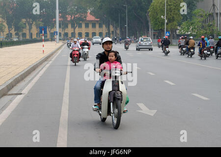 Man riding motor scooters with a young child on the streets of Hanoi, Vietnam, Asia Stock Photo