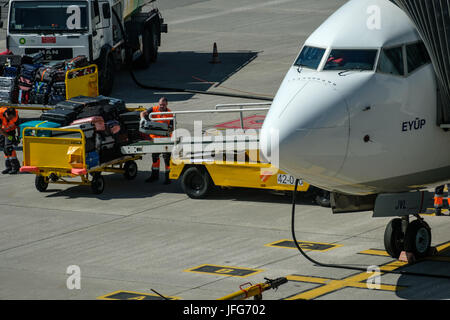 Man loading luggage into airplane at airport tarmac Stock Photo