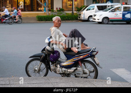 Old vietnamese man resting on this motorcycle Stock Photo