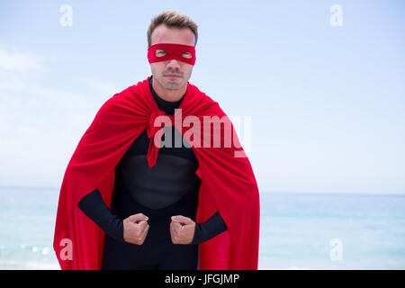 Serious man in superhero costume standing at sea shore Stock Photo