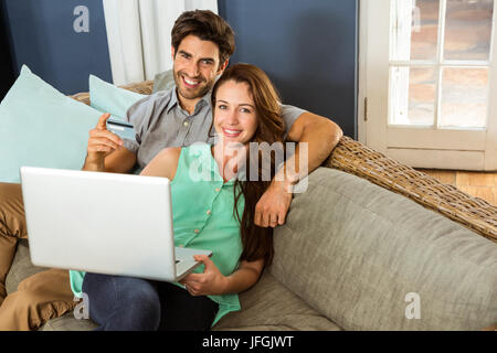 Young couple sitting on sofa and doing online shopping Stock Photo