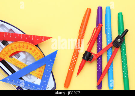 Multicolored rulers and pen on yellow background Stock Photo