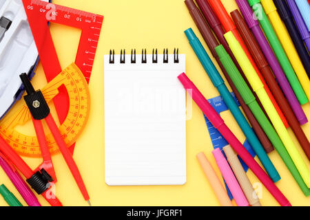 Multicolored pen, rulers and notebook on yellow background Stock Photo