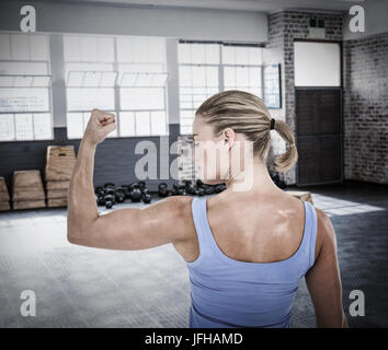 Composite image of rear view of muscular woman flexing muscles Stock Photo