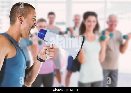 Composite image of angry male trainer yelling through megaphone Stock Photo