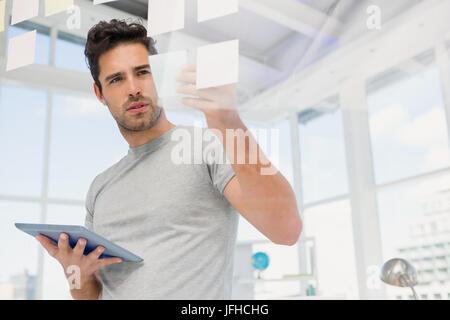Man holding digital tablet and looking at sticky notes Stock Photo