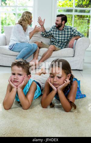Upset children lying against parents fighting at home Stock Photo