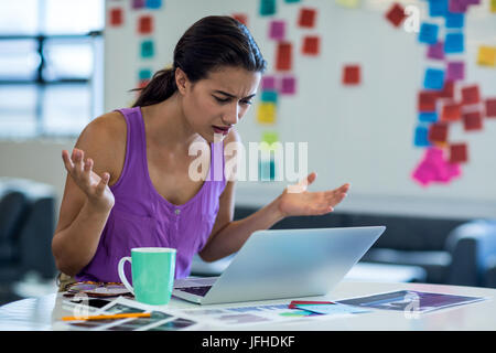 Young woman looking surprised while using the laptop Stock Photo