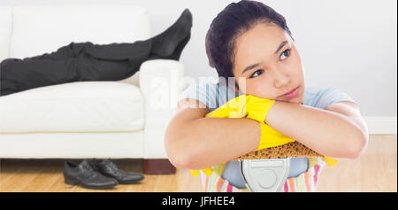 Composite image of troubled woman leaning on a mop Stock Photo