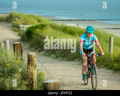 Woman riding bike near beach and sea Stock Photo