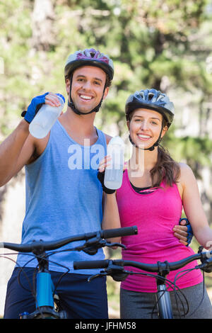 Portrait of young couple drinking water at forest Stock Photo
