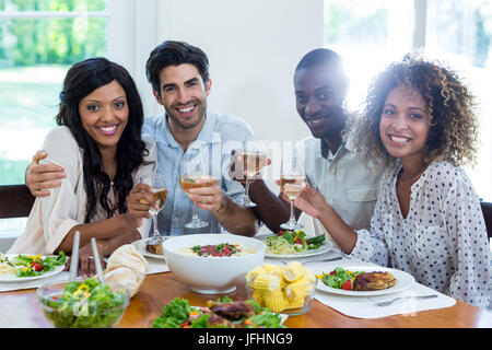Two couples holding wine glass while having meal Stock Photo