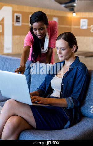 Colleagues interacting with each other using laptop Stock Photo