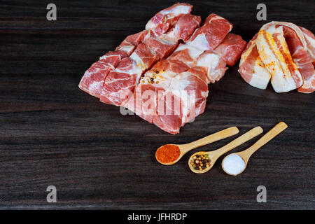 Raw pork bacon slices, rashers, spices, rose peppercorns and fresh rosemary leaves on black slate board, close up, high angle view Stock Photo