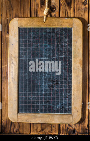 Aged black chalkboard for studying on a grunge wooden wall background. Stock Photo