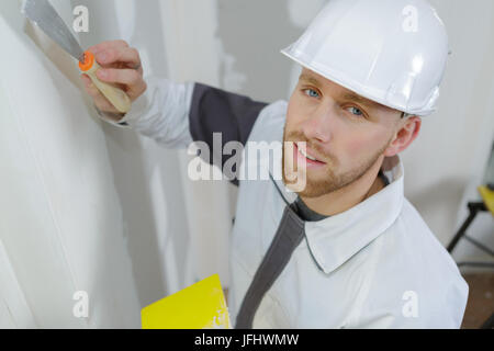 manual worker with wall plastering tools inside a house Stock Photo