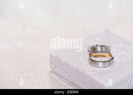 Wedding rings made of gold and platinum with diamonds on white precious jewellery box Stock Photo