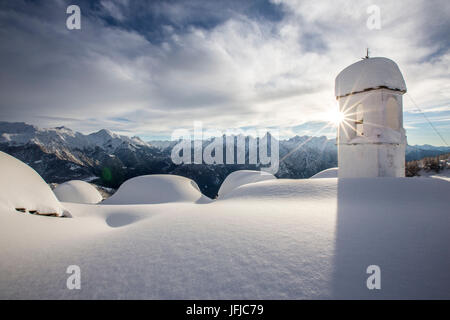 Winter sun shining behind the pictoresque bell tower at Alpe Scima after an heavy snowfall, Valchiavenna, Valtellina Lombardy Italy Europe Stock Photo