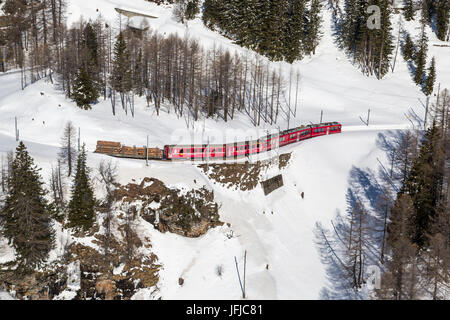 Aerial view of the red Bernina train coming from Bernina Pass in winter, Poschiavo Valley, Canton of Grisons Switzerland Europe Stock Photo