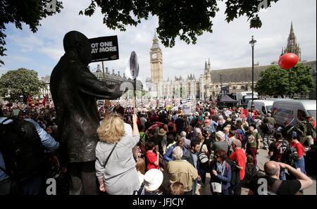 People stand next to the statue of Nelson Mandela in Parliament Square, London, after they march through the city as they took part in an anti-austerity protest. Stock Photo