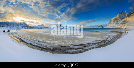 Hiker admire the golden sunrise over a strip of land where the snow has melted, Haukland Lofoten Islands Norway Europe Stock Photo