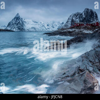 Waves crashing on the cliffs near the houses of the fishermen, Hamnøy, Lofoten Islands Northern Norway Europe Stock Photo