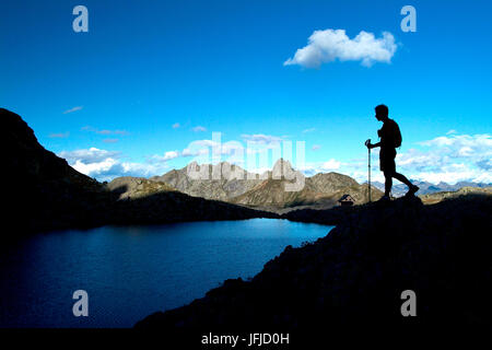 Hiker on Piazzotti lake at sunset near Benigni refuge which stands in between Gerola valley and Brembana valley, Pescegallo Alps Orobie, Valtellina Lombardy, Italy Europe Stock Photo